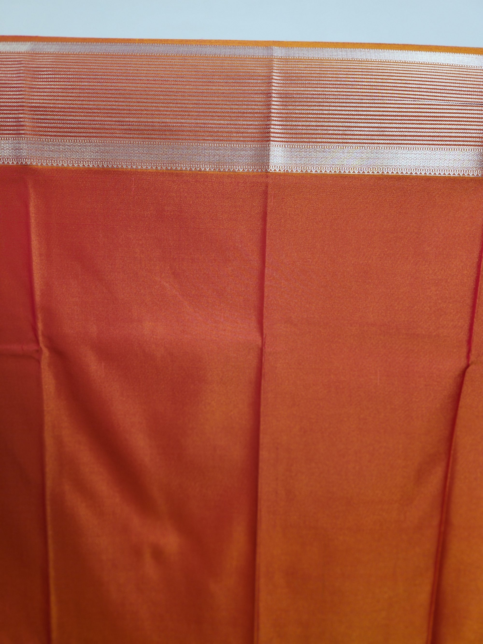 Rust Orange Semi Kanchi Saree with Silver Zari & Flower Butta Design